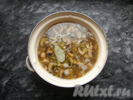 Когда картофель в кастрюле будет практически готов (станет достаточно мягким), добавить в кастрюлю грибы, обжаренные с овощами, а также измельчённый чеснок, лавровый листик, всыпать приправу для супа, перемешать.