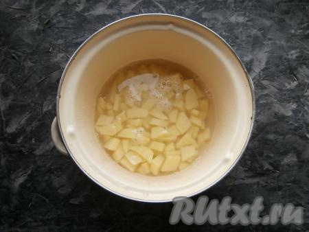 Лук, чеснок и морковку очистить. Картофель очистить, вымыть, нарезать в кастрюлю небольшими кусочками. Залить 2 литрами воды, поставить кастрюлю на огонь, довести до кипения. Воду посолить, варить картошку на небольшом огне 20 минут.