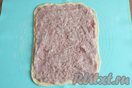 Визуально разделите фарш на две части. Одну часть фарша распределите по раскатанному пласту теста.