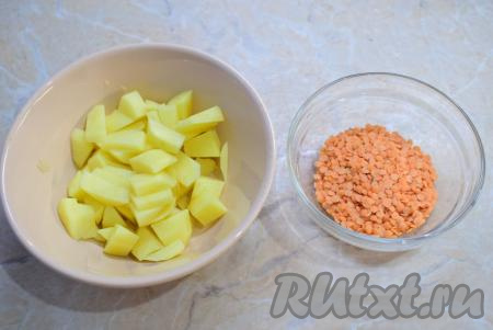 Для супа подготовьте картофель и чечевицу. Картофель очистите, промойте и нарежьте небольшими кусочками. Опустите нарезанный картофель в кипящий бульон (или воду) и варите минут 10 (до полуготовности). Красную чечевицу можно предварительно не замачивать, её достаточно будет просто промыть. 