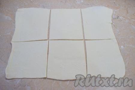 Стол слегка присыпьте мукой. Пласт слоёного теста немного раскатайте и разрежьте на 6 одинаковых квадратиков.