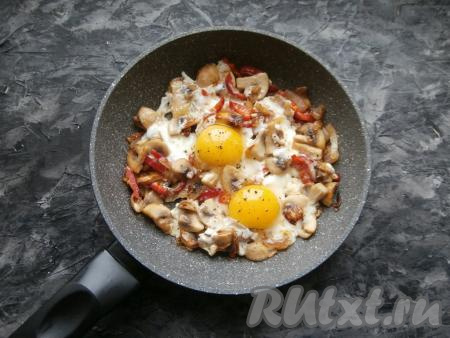 Вбить в сковороду яйца, посолить по вкусу и поперчить, прикрыть сковороду крышкой и на медленном огне выдержать яичницу с шампиньонами и луком 3-4 минуты.&nbsp;