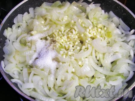 Добавляем нарезанный чеснок, сахар и перемешиваем. Уменьшаем огонь, накрываем сковороду крышкой и тушим лук 30 минут, помешивая время от времени.