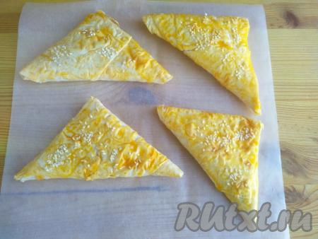 Аналогично сформировать остальные изделия в виде треугольных конвертов. Смазать наши заготовки самсы&nbsp;желтком, посыпать сверху кунжутом. Выложить самсу на противень, застеленный бумагой&nbsp;для выпечки.