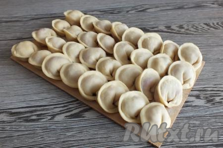 Сформированные пельмени с начинкой из мяса и сыра выкладывайте на доску, припылённую мукой, в один слой. Пельмешки можно заморозить впрок, отправив в морозилку, или сразу же отварить.