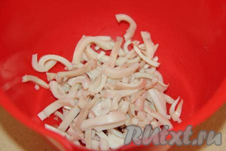 Нарезать кальмара на тонкие полоски и выложить в салатник.