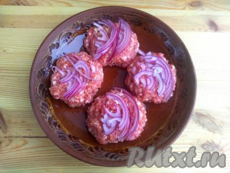 Лук очистить от шелухи, нарезать тонкими полукольцами и выложить поверх котлет.