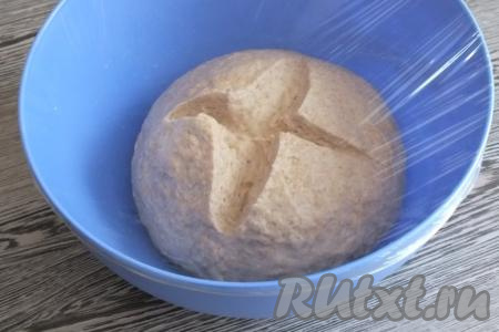 На тесте сделайте крестообразный разрез. Миску с тестом затяните пищевой плёнкой и поставьте в тёплое, без сквозняков место, примерно, на 1 час 15 минут.