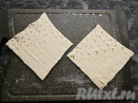 Слоёное тесто немного разморозить, на поверхности, припылённой мукой, разрезать на квадраты размером 13 см х 13 см (у меня получилось 4 квадрата). Взять один квадрат, в противоположной стороне от одного угла острым ножом сделать небольшие разрезы в хаотичном (или чётком) порядке. Разрезы делать до середины квадрата, оставляя другую часть в первоначальном виде (см. фото).