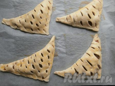 Сложить слойки с повидлом на противень, застелив его пергаментной бумагой, смазать желтком.