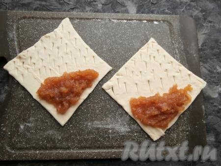 На половину угла, который остался без разрезов, выложить по 1-2 столовых ложки повидла, размазать его ложкой по неразрезанному углу, оставляя края чистыми.