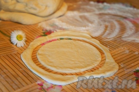 Дрожжевое тесто разделить на части (я разделила на 18 частей, в результате с использованием обрезков теста у меня получилось 20 пирожков). На поверхности, припылённой мукой, раскатать каждую часть теста, затем формой (или блюдцем) вырезать "заготовки" для каждого пирожка.
