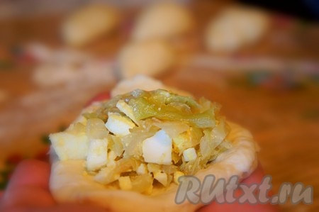 На каждую приготовленную "заготовку" для пирожка выложить по 1-2 столовых ложки начинки из капусты и яиц, немного утрамбовать начинку рукой.
