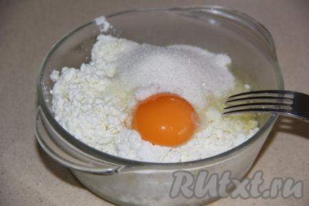 Включить духовку и оставить разогреваться до 200 градусов. Для приготовления начинки соединить творог, яйцо и сахар, по желанию, добавить ванилин, а затем перемешать до однородности с помощью вилки. Начинка для ленивых ватрушек у меня получилась не жидкой. Густота начинки во многом зависит от качества творога, если начинка получилась очень жидкой и она будет плохо держаться на кусочках батона, тогда можно добавить 0,5-1 чайную ложку манки.