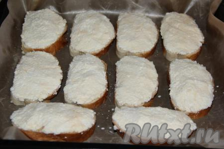 Выложить смоченные в молоке кусочки батона на застеленный (или смазанный) противень. Равномерно выложить начинку на каждый кусочек батона.