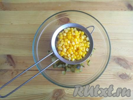 Консервированную кукурузу откинуть через сито, удалить излишки жидкости. Выложить зёрна кукурузы в миску к огурцам.
