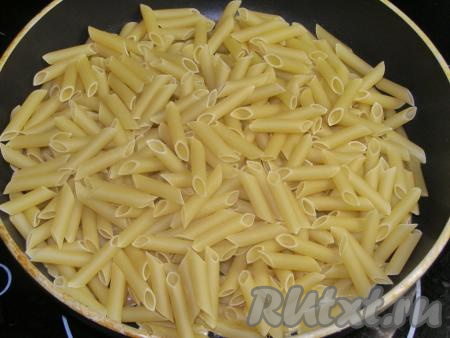 В сковородку наливаем, примерно, 1 столовую ложку подсолнечного масла, немного разогреваем на сильном огне и высыпаем в сковороду сухие макароны.