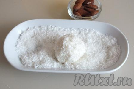 Аккуратно поднимите краешки творожной массы, соедините их, формируя шарик с орешком внутри. Обваляйте творожный шарик в кокосовой стружке со всех сторон.