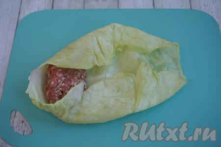 Начинаем формировать наши голубцы. На капустный лист выкладываем небольшой шарик фарша весом, примерно, 100-120 грамм.&nbsp;Фарш кладём ближе к основанию листа, подворачиваем капусту с двух боков (слева и справа от фарша).