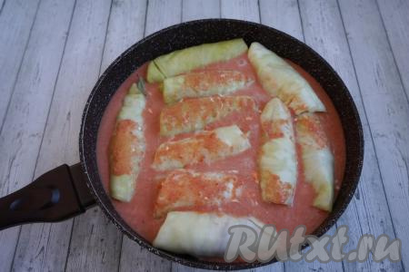 Заливаем наши голубцы получившимся томатно-сметанным соусом, закрываем сковороду крышкой, ставим на огонь, даём закипеть соусу, а затем тушим на небольшом огне 25-30&nbsp;минут.