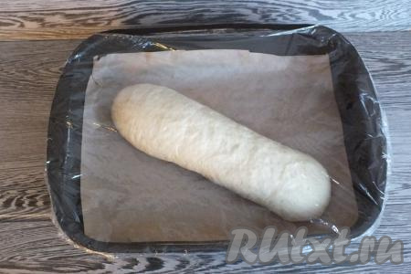 Выложите получившийся рулет швом вниз в форму для выпечки, застеленную пергаментом. Затяните форму с рулетом плёнкой и оставьте на 40 минут для расстойки.