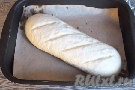 Разогрейте духовку до 200 градусов. На заготовке острым ножом сделайте косые надрезы, смажьте тесто водой и поставьте выпекаться в разогретую духовку на 35-40 минут.