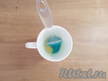 В кружку объёмом не менее 350 мл, пригодную для микроволновки, выложить небольшой кусочек сливочного масла, поставить в микроволновку секунд на 30. Далее с помощью силиконовой кисточки смазать кружку внутри растопленным сливочным маслом.