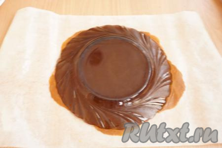 Достаём вначале один кусочек теста из холодильника и начинаем раскатывать. Тесто само по себе липкое, а коржи нужно сделать тонкими (толщиной, примерно, 0,5-0,6 см). Поэтому раскатывать я рекомендую сразу на бумаге для выпечки. Чтобы тесто легче раскатывалось, советую обильно смазать бумагу и скалку растительным маслом, тогда коржи удастся довольно просто раскатать. Корж обрезаем по форме тарелки нужного вам диаметра, затем густо накалываем вилкой. Обрезки не выбрасывайте, их мы тоже испечём и используем для приготовления крошки для обсыпки торта.