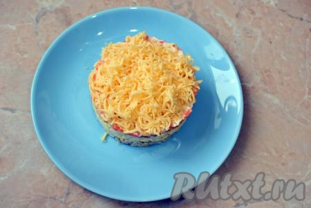 Последним слоем выложите в виде пышной шапочки сыр, натёртый на мелкой тёрке (смазывать майонезом не нужно). Снимите с салата форму и подавайте его к столу.