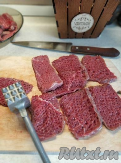 Блюдо запекается в духовке, поэтому все ингредиенты поочередно выкладываем на противень. Для начала подготовим говядину. Нарезаем мясо на достаточно большие ломтики толщиной около 1 см (куски мяса не должны быть толще 1 см, иначе говядина в процессе запекания с картошкой полностью не приготовится) и отбиваем с двух сторон кухонным молоточком.