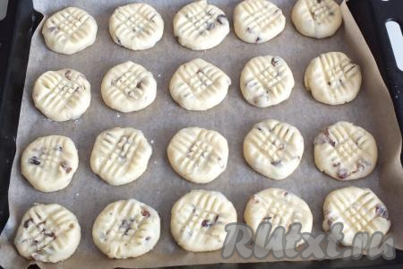 Противень застелите пекарской бумагой. Оторвите кусочек теста размером с теннисный шарик (у меня вес каждой заготовки получился 43-45 грамм). Скатайте этот кусочек теста в шарик, выложите на противень, прижмите слегка вилкой. Таким образом сформируйте всё печенье. Перед формовкой каждой печенюшки обсыпайте руки мукой, чтобы тесто не прилипало к рукам. Выкладывайте печенье на небольшом расстоянии друг от друга. Поставьте противень в разогретую до 180 градусов духовку на 10-15 минут. Учитывайте особенности своей духовки.