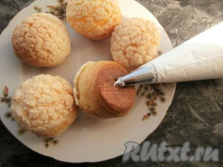 Крему дать остыть, переложить его в кондитерский мешок с насадкой для эклеров или просто с насадкой с отверстием и, сделав снизу пирожных небольшое отверстие (ножом или насадкой), наполнить их кремом.