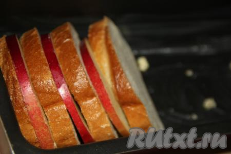 Форму для выпечки (я использовала прямоугольную форму) смазать сливочным маслом. Выложить в форму, чередуя, кусочки батона и кружочки яблок.