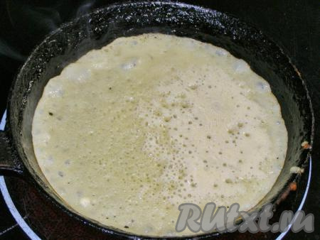 Ставим сковороду на огонь, чуть меньше максимального, наливаем совсем немного масла и сильно нагреваем, пока не появится лёгкий дымок. Чтобы блины получились с красивым рисунком, лучше всего использовать чугунную сковородку. Когда сковорода хорошо разогреется, половником наливаем в неё блинное тесто и круговыми движениями распределяем его по всей поверхности сковороды. Жарим блин около 1 минуты, пока тесто слегка не потемнеет.