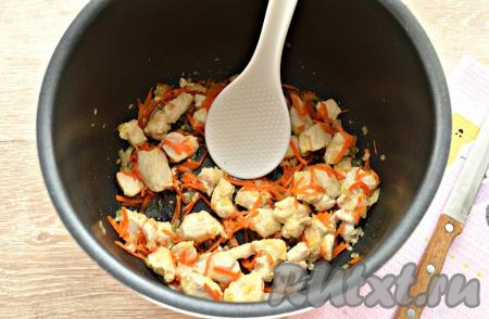 3 столовые ложки растительного масла влить в съёмную чашу мультиварки. Включить программу «Жарка». Поместить в чашу нарезанные морковку и лук, обжарить, помешивая, минуты 3. Затем добавить кусочки курочки, перемешать и обжаривать с овощами в течение 7 минут, не забывая периодически перемешивать.