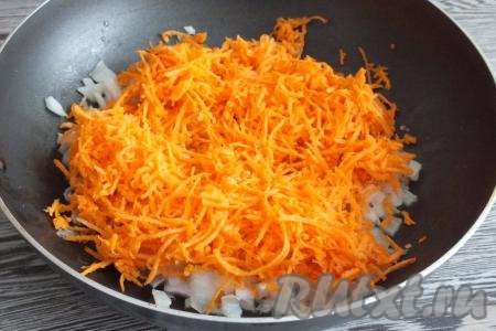 Когда лук станет мягким, выложите к нему очищенную и натёртую на средней тёрке морковь, хорошо перемешайте и обжаривайте, помешивая, в течение 5 минут.