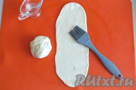 Теперь возьмите 2 получившиеся половинки. Каждую половинку раскатайте в пласт длиной 16 см и шириной 10 см, смажьте растительным маслом.