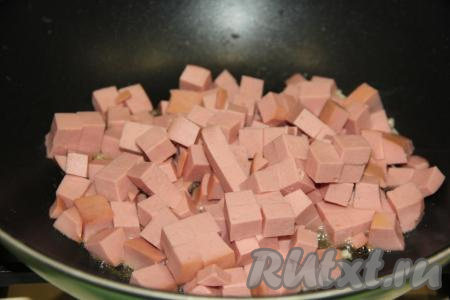 Затем выложить кубики колбасы в сковороду.