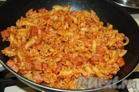 Перемешать макароны с колбасой, потомить на среднем огне в течение&nbsp;5 минут, затем добавить натёртый на тёрке сыр (немного натёртого сыра можно оставить для подачи), перемешать и выключить огонь.