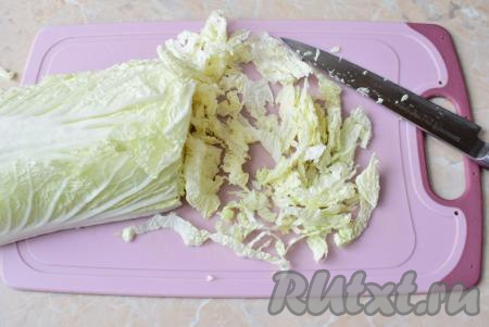 С пекинской капусты снимите 2-4 верхних листика (они нам не пригодятся). Затем разрежьте кочан вдоль на 2 половины. Нарежьте достаточно тонко одну из половинок пекинской капусты (для этого салата нам ориентировочно понадобится 150 грамм нарезанной капусты), переложите в объёмную чашу.