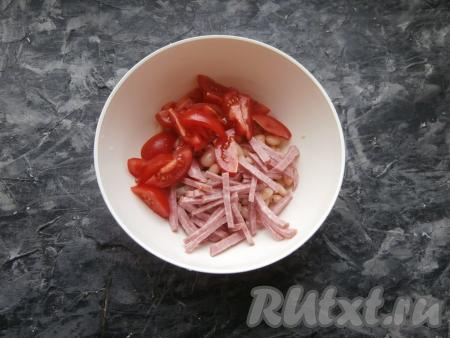К фасоли добавить нарезанную соломкой (или тонкими брусочками) копчёную колбасу и нарезанные&nbsp;дольками помидоры.