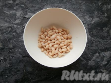 Сухую фасоль нужно с вечера полностью залить чистой холодной водой и оставить на ночь. На следующий день воду, в которой замачивалась фасоль, слить. Переложить фасоль в кастрюлю, залить чистой водой, отправить на огонь, после того как вода закипит (подсаливать её не нужно!), варить её на небольшом огне до готовности (время варки может составлять от 40 минут до 1,5 часов). Фасолинки должны стать мягкими, но при этом они не должны развариться. У меня фасоль варилась около 50 минут, время варки зависит от сорта фасоли. С готовой отваренной фасоли слить воду, а затем остудить. Можно для этого салата взять и покупную консервированную фасоль, слив с неё жидкость (при желании, слив жидкость, фасоль можно промыть проточной водой и немного обсушить, выложив в сито).