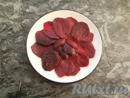 Свеклу в кожуре отварить в подсоленной воде в течение 45-60 минут (до готовности - полностью готовый корнеплод будет легко прокалываться ножом), остудить, очистить и нарезать тонкими ломтиками, которые выложить внахлёст на плоскую тарелку в виде круга.