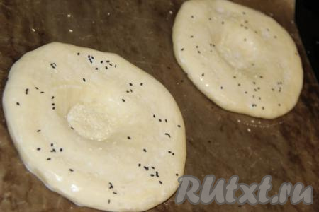 По прошествии времени лепёшки станут пышными, смазать их молоком (или водой) с помощью кисти и присыпать семенами кунжута (у меня чёрный и белый кунжут).