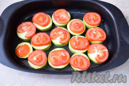 Помидоры берите небольшие, примерно, по размеру кабачка. Помойте помидоры и нарежьте кружочками. На каждый кабачок выложите по кружочку помидора. Зубчики чеснока очистите и пропустите через чеснокодавилку. На каждый помидор разместите немного выдавленного чеснока, слегка присолите.