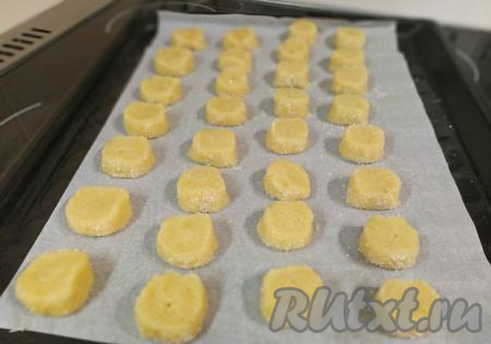 Противень (или форму для выпекания) застелить бумагой для выпечки и переложить заготовки из песочного теста. Выкладывать нужно на некотором расстоянии друг от друга, так как в процессе выпечки печенье немного увеличивается в размере.
