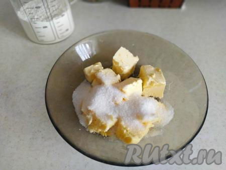 Сливочное масло достать из холодильника и оставить согреваться при комнатной температуре до тех пор, пока оно не станет мягким. В глубокую тарелку (или миску) положить размягчённое масло, добавить 50 грамм сахара и ванильный сахар. Тщательно растереть масло с сахаром вилкой. При желании, можно слегка взбить массу миксером.