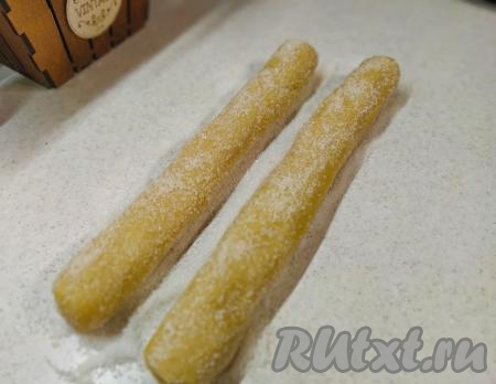 Далее на поверхность, на которой формировались колбаски, насыпать 50 грамм сахара. Несколько раз покатать полученные "колбаски" из теста по сахару. При этом проследите, чтобы сахар равномерно распределился по всей поверхности теста. Здесь можно проявить немного фантазии. Например, к сахару добавить мак или кунжутные семечки. А можно вместо белого сахара насыпать коричневый.