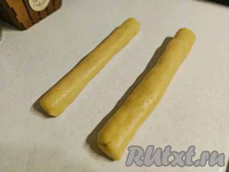 По прошествии времени достать тесто из холодильника. На ровной поверхности каждую часть песочного теста скатать в "колбаску" (получатся 2 "колбаски"). Диаметр "колбасок" зависит от того, какого размера хотите получить печенье. Если любите маленькие печеньки - "колбаска" должна быть тоньше, если любите большие печенюшки - соответственно "колбаска" должна быть побольше.