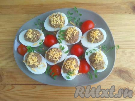 Яичные белки заполнить грибной массой, присыпать натёртым желтком. Выложить фаршированные яйца на тарелку для подачи. Блюдо, по желанию, можно украсить помидорами черри, свежей зеленью. Подать закуску к столу.